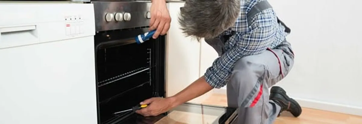Oven repair technician inspecting and servicing an electric oven in Columbia, SC