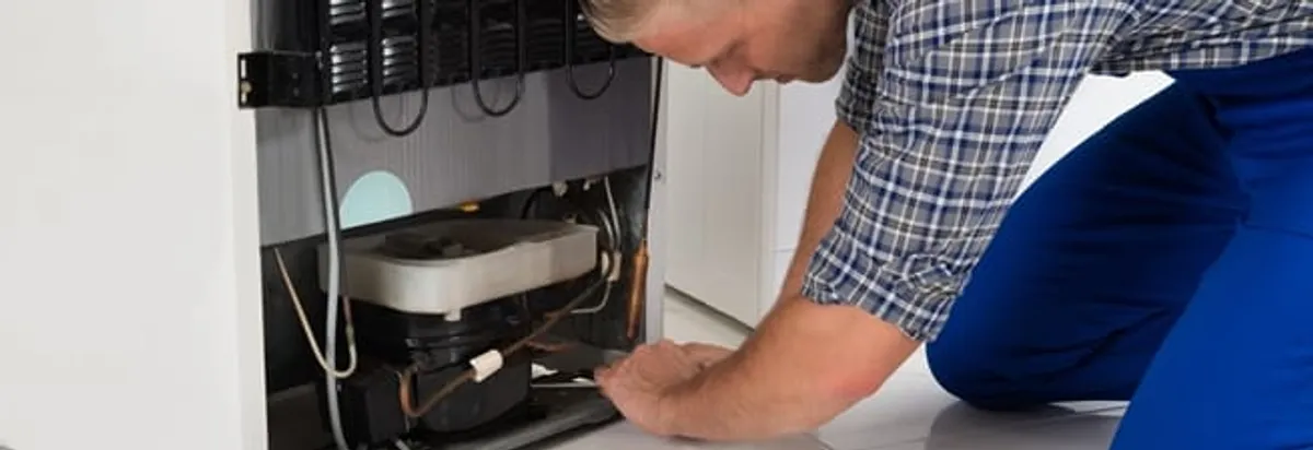 Refrigerator repair technician servicing the compressor and condenser area in Columbia, SC