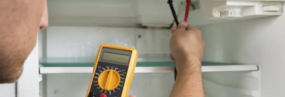 Refrigerator repair technician testing electrical components with a multimeter in Columbia, SC