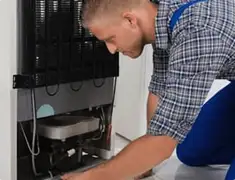 Refrigerator repair technician servicing the compressor and condenser area in Columbia, SC