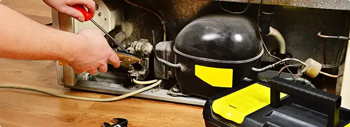 Refrigerator repair technician fixing the compressor and wiring in Columbia, SC