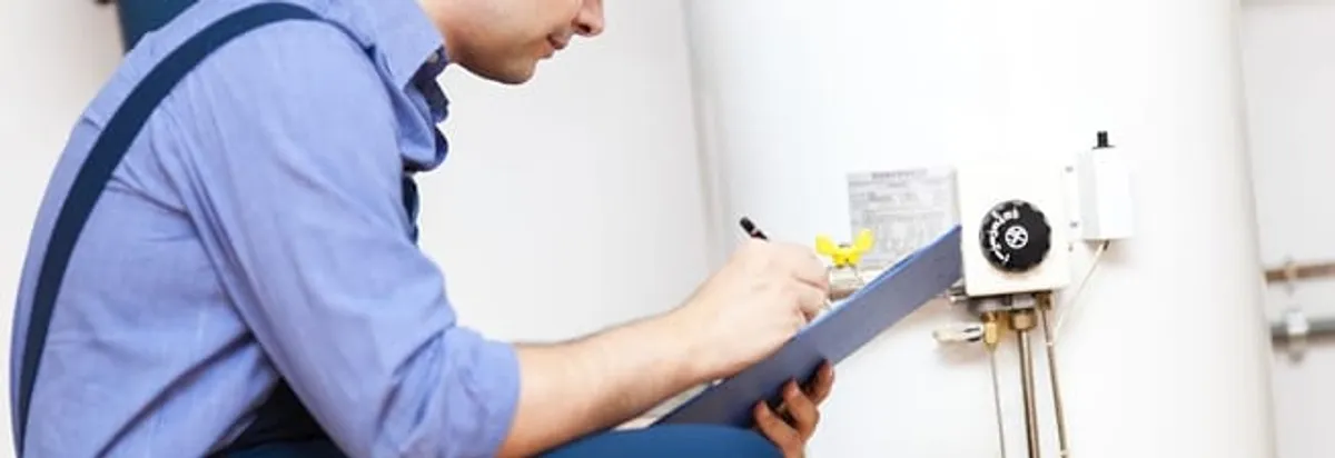 Water heater repair technician inspecting the unit and recording service notes in Columbia, SC